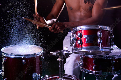 close-up of black male holding drum sticks in water, performing music