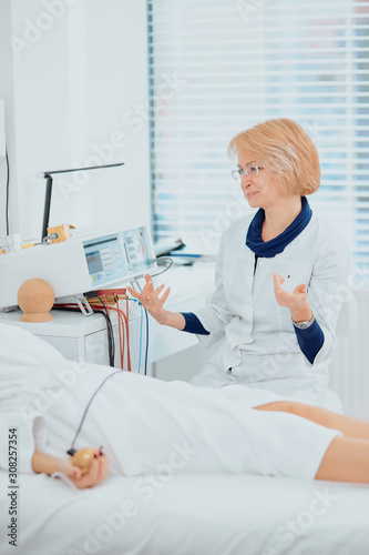 adult doctor in eyeglasses and white bathrobe  uniform sit explaining cause of illness to patient lying on bed and listening to him