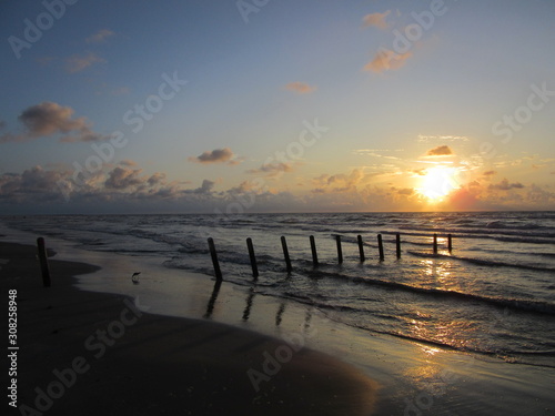 Sunrise is reflected in the water and on the sand, Packery Channel Jetty Beach, Padre Island, Texas