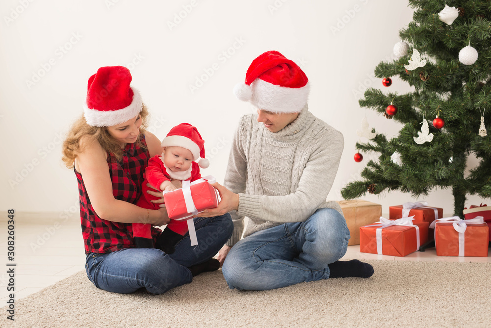 Holidays, children and family concept - Happy couple with baby celebrating Christmas together at home. Holidays, children and family concept - Happy couple with baby celebrating Christmas together at home.