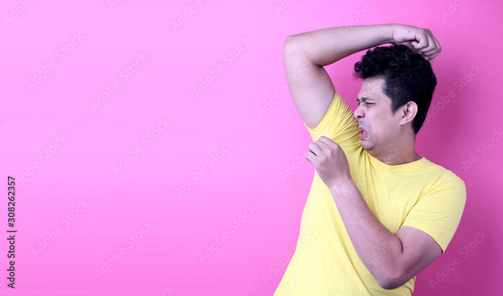  Asia Man sweating excessively smelling bad isolated on pink  background in studio With copy space.