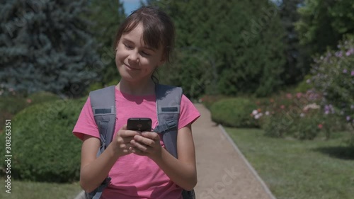 Teen girls with smartphone. Cute teenage girl in the park with a backpack with a smartphone. photo