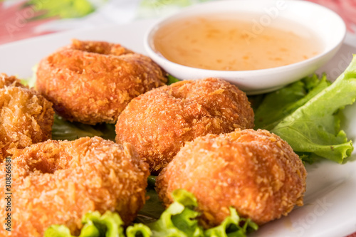 fried crab meat ball with sweet sauce for dinner served with vegetable in the white dish on the table. it's unhealthy food because it's cooked by fried with oil. favorites food for people in Thailand