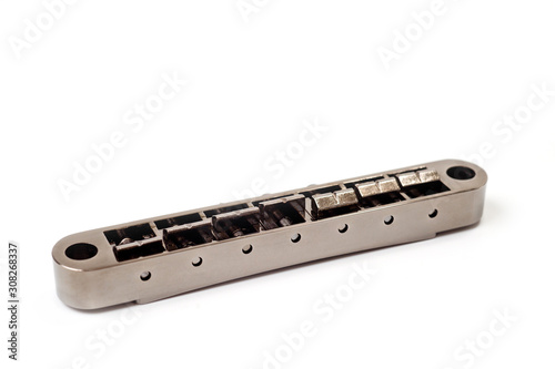 Metallic guitar bridge, suitable for electric and acoustic guitars, disassembled, closeup shot on a white background