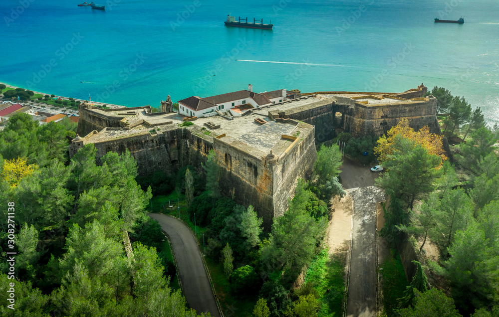 Aerial view of fortress Sao Felipe in Setubal Portugal, star shaped military base protecting the city and the harbor with bastions above the turquoise  water of the Atlantic ocean and the Sado estuary