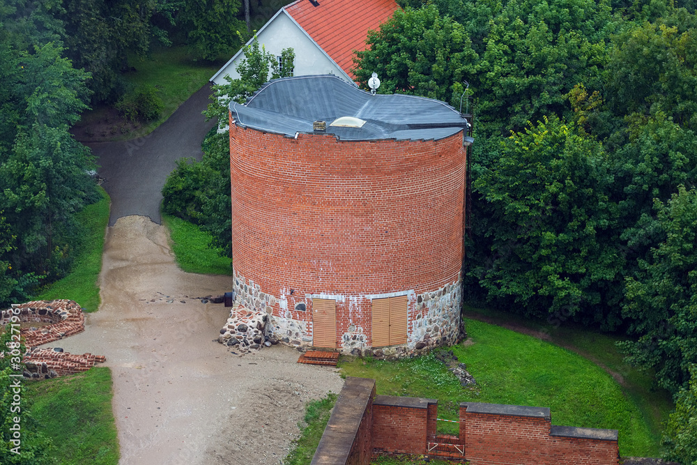 Naklejka premium Aerial view on the small tower from the main big tower of medieval Turaida Castle in cloudy, foggy and rainy day, Sigulda, Latvia. It is reconstructed castle, which was founded in 1214. Soft focus