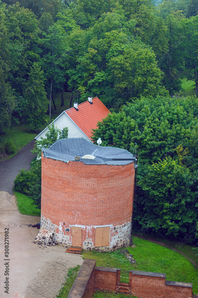 Naklejka premium Aerial view on the small tower from the main big tower of medieval Turaida Castle in cloudy, foggy and rainy day, Sigulda, Latvia. It is reconstructed castle, which was founded in 1214. Soft focus
