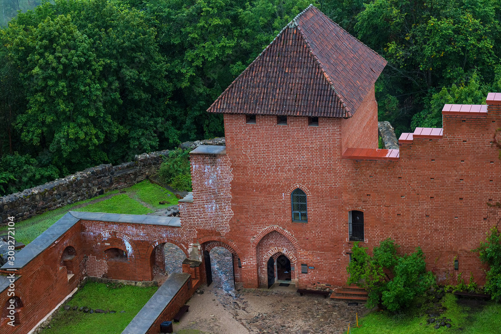 Aerial view on the courtyard and red brick buildings of medieval Turaida Castle from the main big tower in cloudy, foggy and rainy day, Sigulda, Latvia. Soft focus.