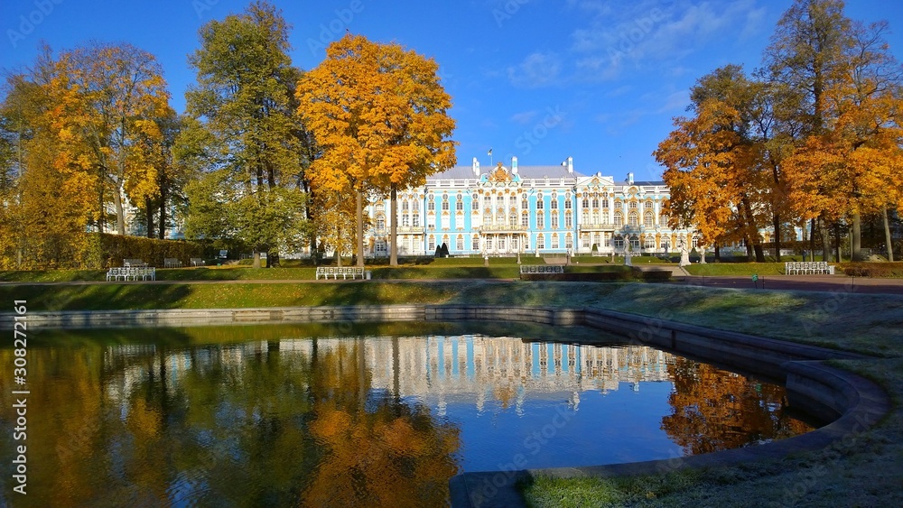 Catherine Palace and Park in Pushkin, a suburb of St. Petersburg, Russia. A favorite place for excursions and travel of tourists. Reflection of green and orange trees in a pond. Colorful golden autumn