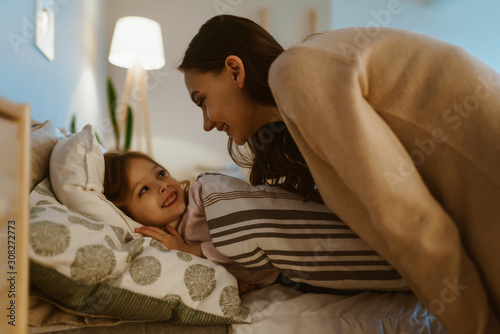 mom puts her daughter to bed and tells her something
