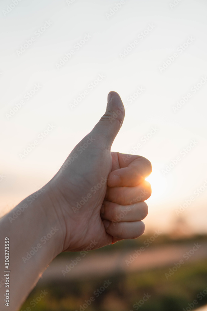 thumb up hand with sunlight sky background. success sign concept thumb up hand with sunlight sky background. success sign concept