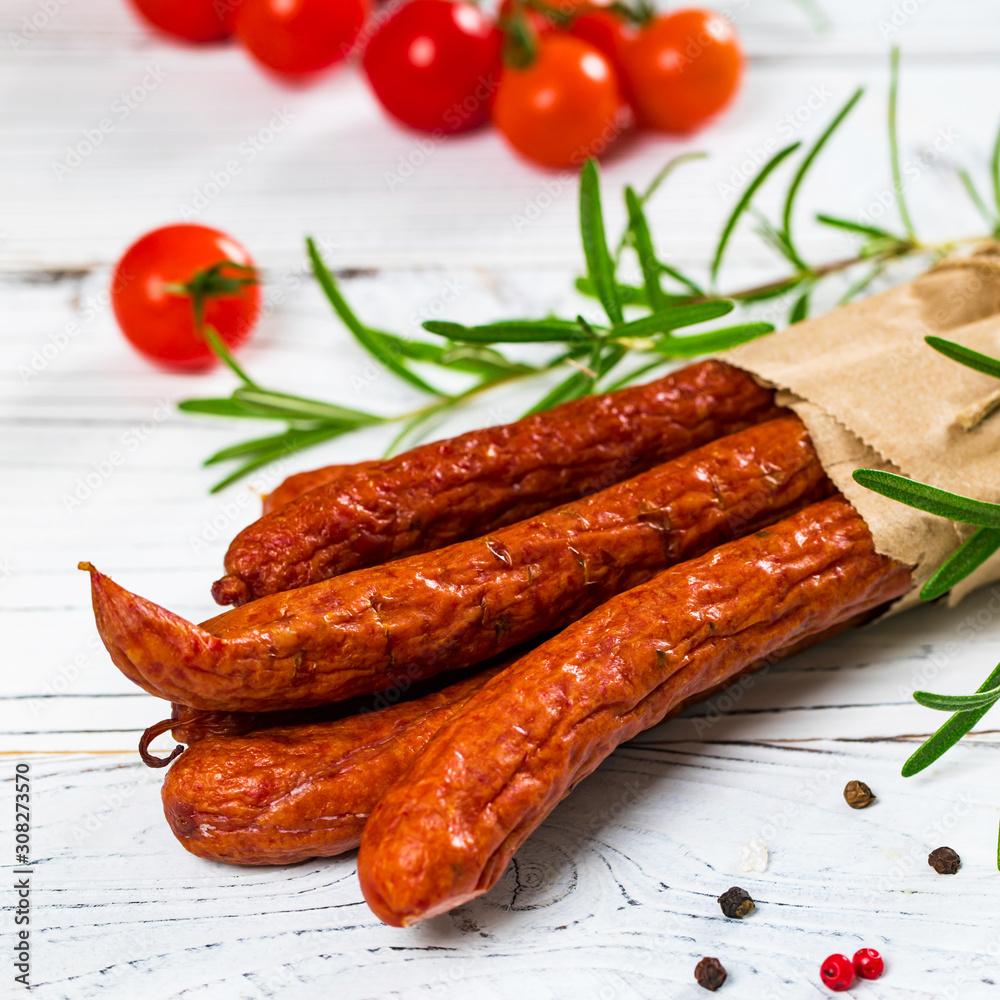 Thin Dry Smoked Polish Sausage Kabanos or Cabanossi on White Wooden Background. Selective focus. Thin Dry Smoked Polish Sausage Kabanos or Cabanossi on White Wooden Background. Selective focus.
