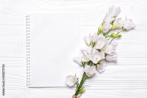 White flowers bells and empty notebook for your text on a white background.
