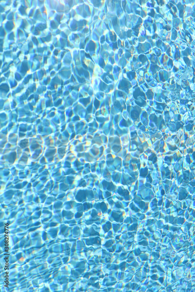 Background of pool water texture. Reflection of sun rays in pool water. Vertical, close-up, cropped shot. Sports and recreation concept.