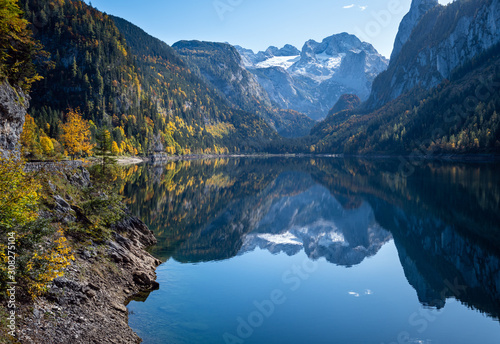 Peaceful autumn Alps mountain lake. Gosauseen or Vorderer Gosausee lake  Upper Austria. Dachstein summit and glacier in far.