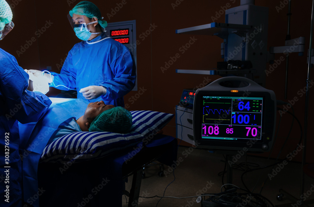 medical team surgeon performing surgery at work with with ECG/EKG monitor showing heart rate for rescue patient in operation room at hospital, medical technology, health care cancer, disease concept medical team surgeon performing surgery at work with with ECG/EKG monitor showing heart rate for rescue patient in operation room at hospital, medical technology, health care cancer, disease concept