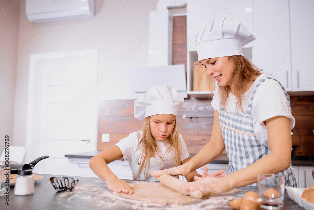caucasian mother and daughter bake together, make dough and use ingredients need for it. Happy teamwork in kitchen of woman and her child caucasian mother and daughter bake together, make dough and use ingredients need for it. Happy teamwork in kitchen of woman and her child