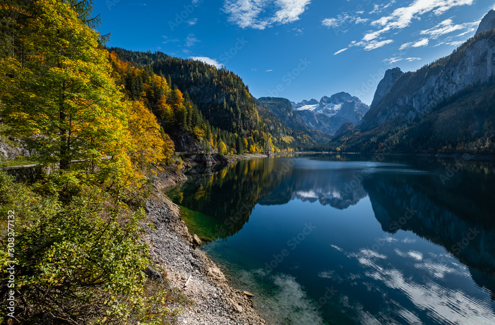 Autumn Alps mountain lake with clouds reflections. Gosauseen or Vorderer Gosausee lake, Upper Austria. Dachstein summit and glacier in far.