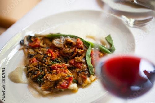 baked fish with vegetables in a restaurant and red wine