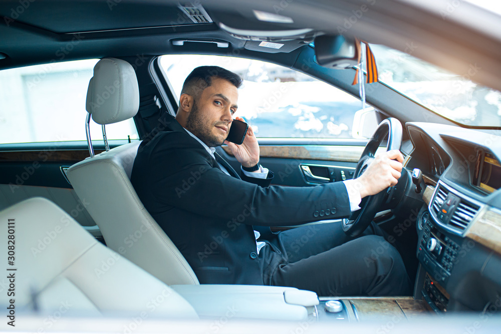 businessman talking on phone about work and driving a car, sit in car of top class, wearing formal wear