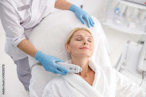 Specialist doing neck lifting in beauty salon photo