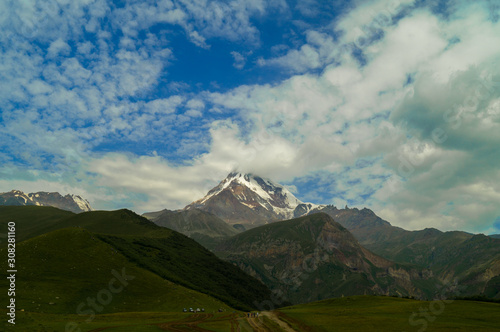  Kazbek. Peak. The highest point of Georgia. High mountain against the sky with clouds. © Aleksey