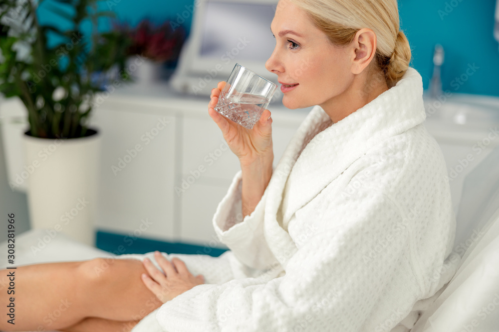Smiling adult woman drinking water in beauty salon Smiling adult woman drinking water in beauty salon