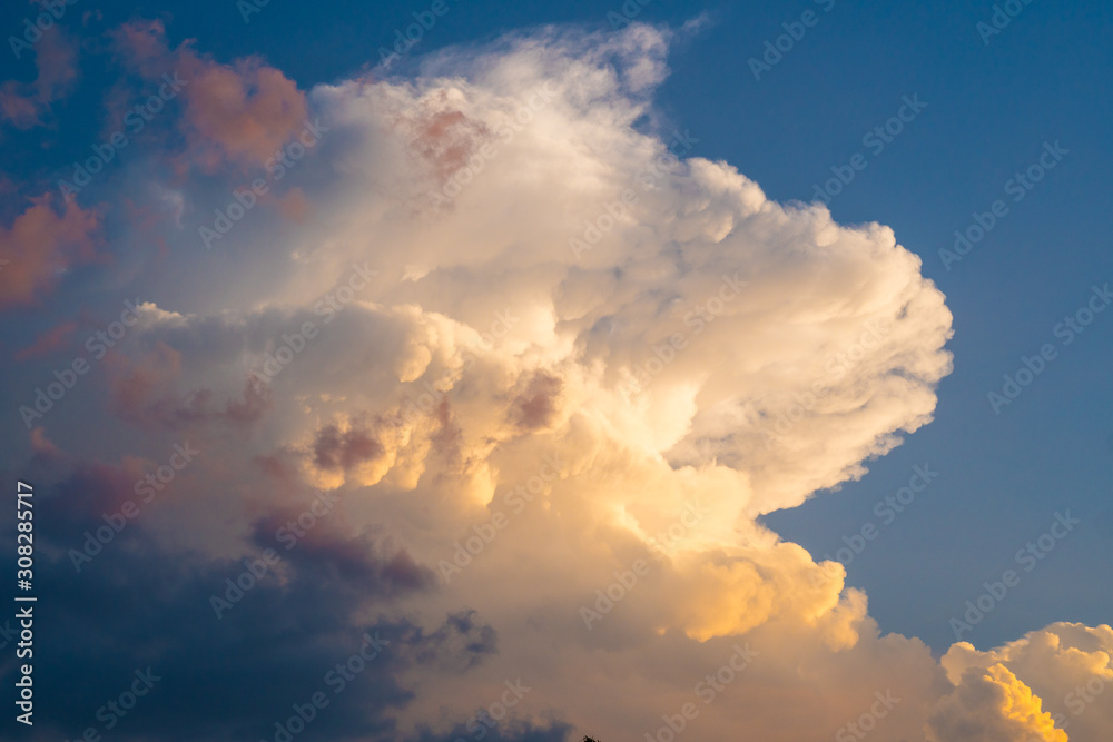 Colorful dramatic sky with sunset colors shining through the white clouds