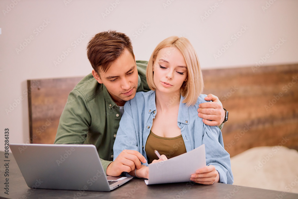 caucasian married couple, handsome man and beautiful woman sit looking for, in search of new house or apartment, mortgage, searching online using laptop