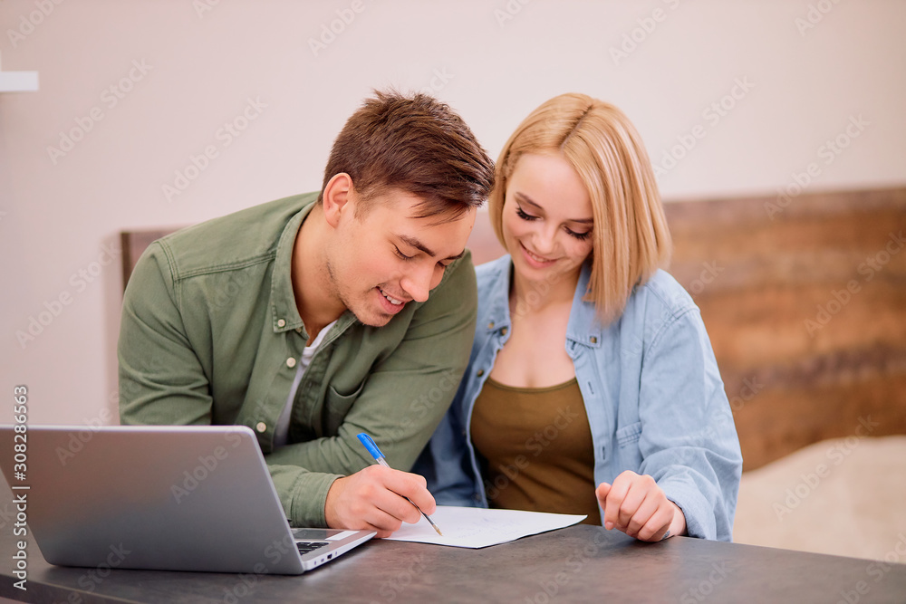 young caucasian man and woman sit with papers, documents and making notes, planning their joint finance at home using laptop young caucasian man and woman sit with papers, documents and making notes, planning their joint finance at home using laptop