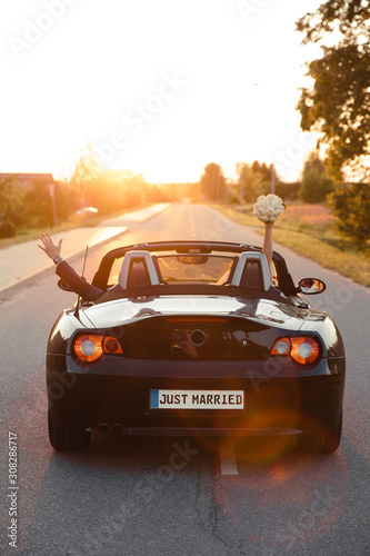 Wedding Just Married sign black rodster cabrio coupe car with bride and groom leaving into sunset in Eastern European Baltic Riga Latvia
