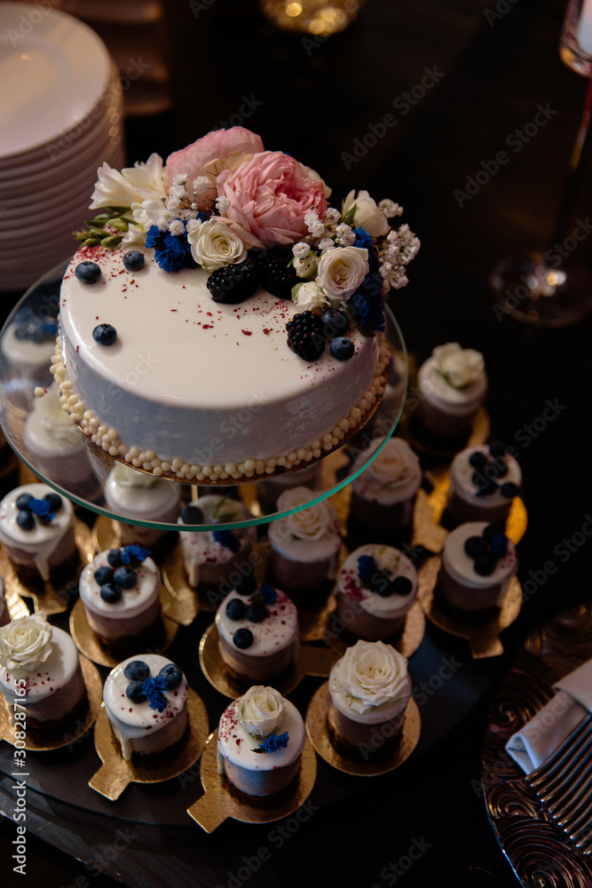 Blueberry with creme decorations wedding reception cake with small cupcakes for guests in Eastern European Baltic Riga Latvia