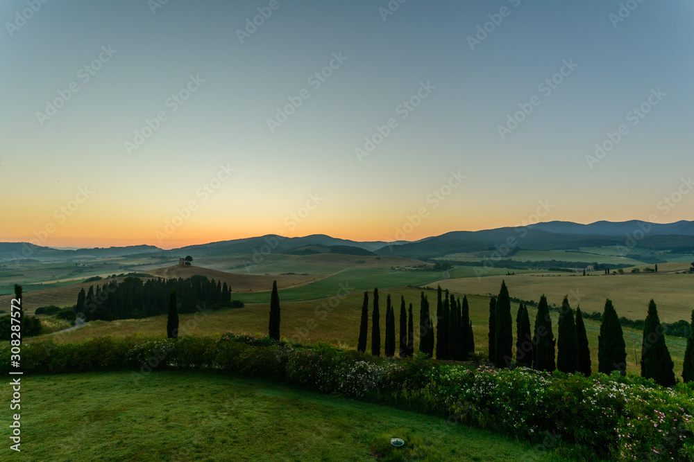 Sonnenaufgang über den Hügeln der Toskana mit Zypressen und Feldern
