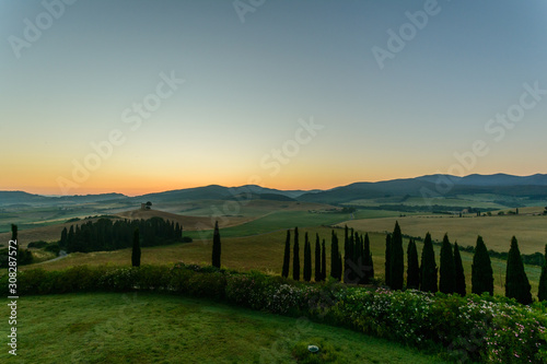 Sonnenaufgang über den Hügeln der Toskana mit Zypressen und Feldern