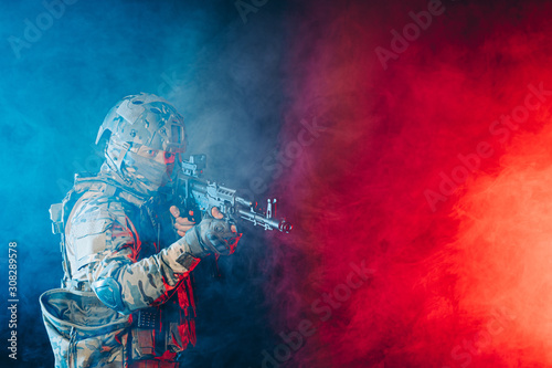 young man in green army wear and helmet shooting rifle at somebody isolated in space with ultra violet rays