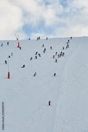 Skiing slope with many unrecognizable skiers coming down