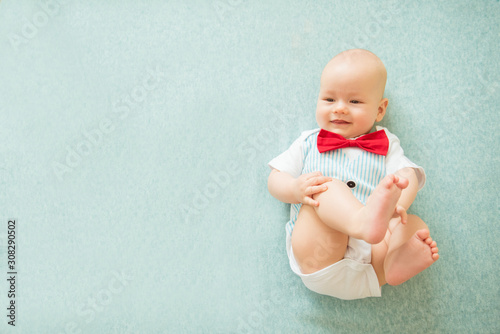 Calm curious baby lying on blue background, top view