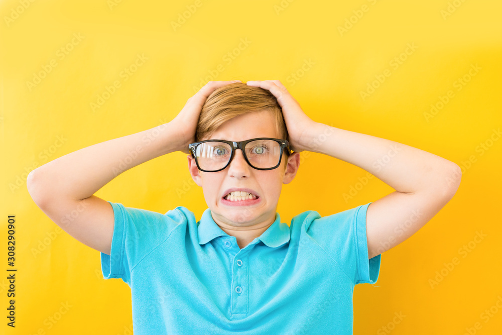 Frustrated boy holding his head on a yellow background. Study, difficulties and problems concept Frustrated boy holding his head on a yellow background. Study, difficulties and problems concept