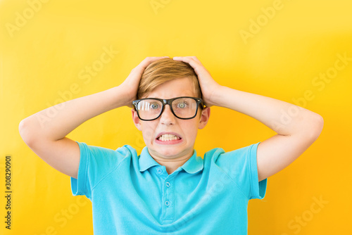 Frustrated boy holding his head on a yellow background. Study  difficulties and problems concept