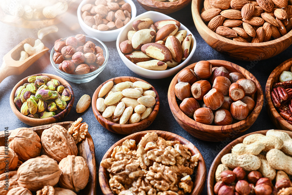 Mixed nuts in wooden bowls on black stone table. Almonds, pistachio, walnuts, cashew, hazelnut. Top view nut photo. Mixed nuts in wooden bowls on black stone table. Almonds, pistachio, walnuts, cashew, hazelnut. Top view nut photo.