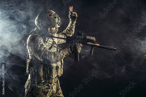 young military man soldier holding gun, wearing special services uniform, stand in smoky space. defend concept
