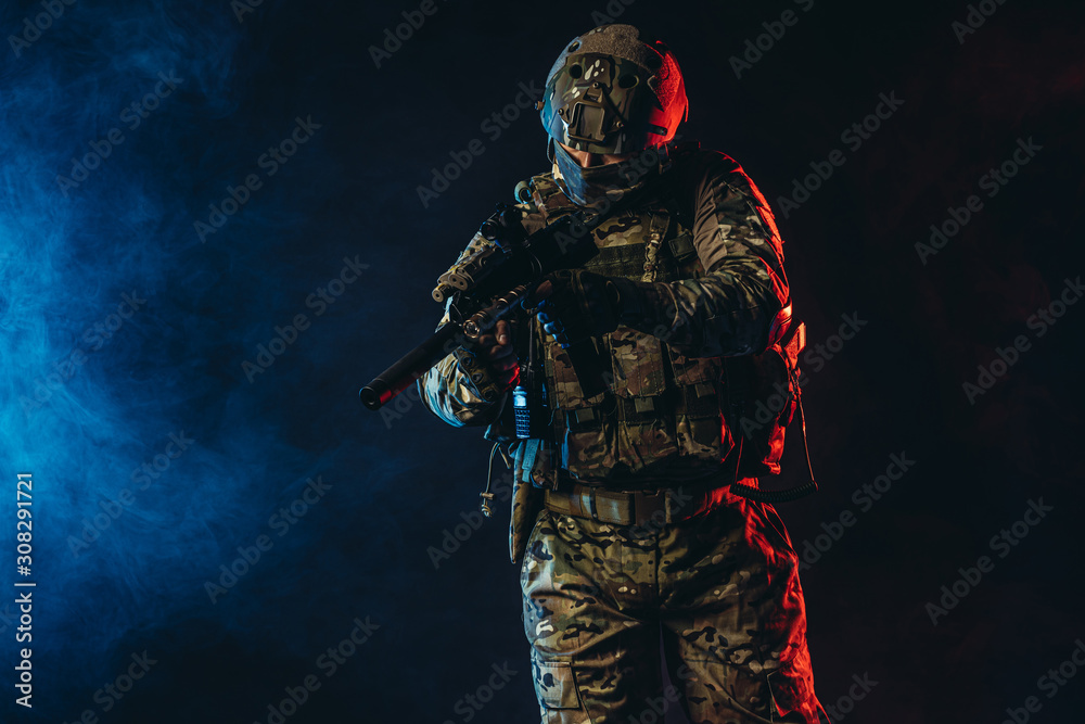 warrior military man wearing green uniform stand with gun rifle isolated over smoky background with ultra-violet rays, in search of enemy