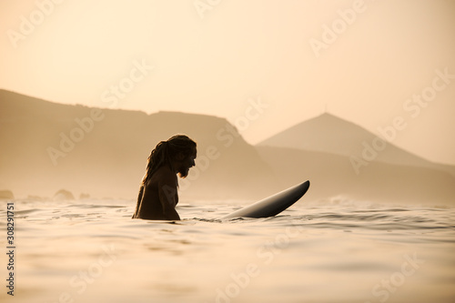 Photography Side view naked man with dreadlocks sitting on the surfing board in the sunset t