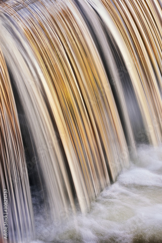 Portage Creek Cascade captured with motion blur and illuminated by reflected color from sunlit trees at sunrise, Milham Park, Michigan