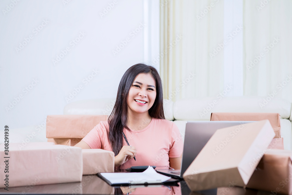 Asian woman smiling to camera while working Asian woman smiling to camera while working