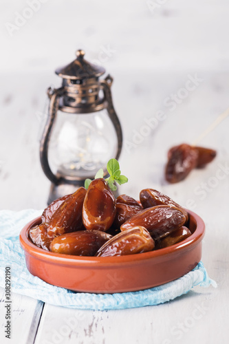 Ramadan lamp and dates still life. Raw sweet dry dates with in a terracotta bowl on a white background. Organic sweeties to healty eating