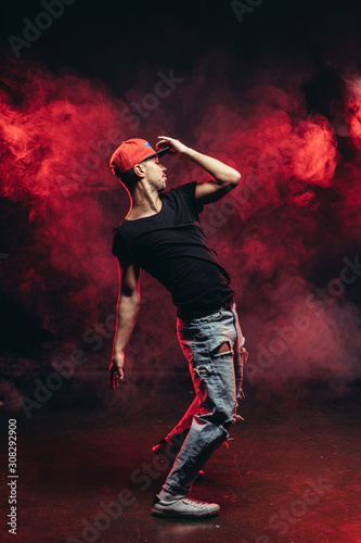 Fototapeta Naklejka Na Ścianę i Meble -  young vigorous male dancing isolated over red smoky space, wearing casual wear. street dance concept
