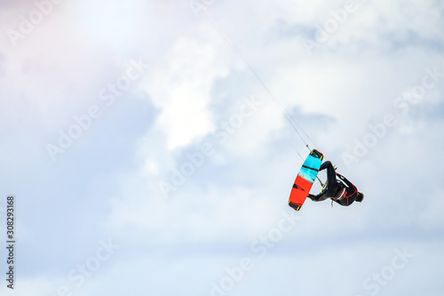 Kite surfing. Kiter makes trick and fly in air on a cloud background.