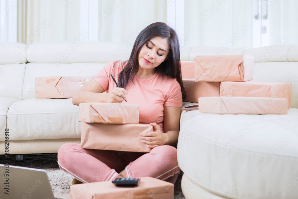 Beautiful Asian woman writing and naming a package Beautiful Asian woman writing and naming a package
