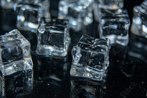 Ice cubes with a drops of water / A lot of different ice cubes on reflection table on black background